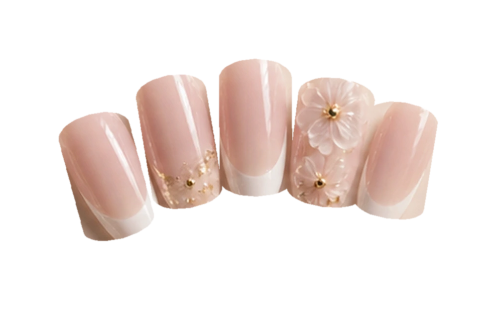 Pale pink French acrylic nails with sculpted white blossoms and tiny gold flecks